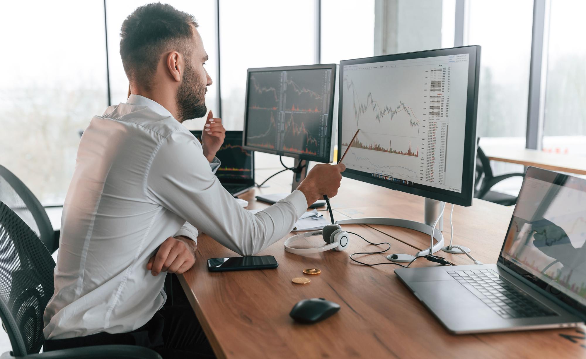Młody analityk przy monitorze z wykresami